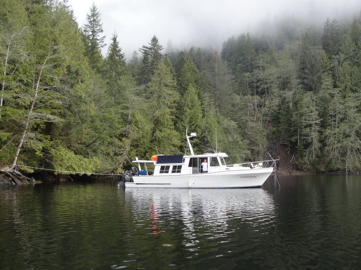 The Cuxhaven trawler yacht anchored in a misty forested cove