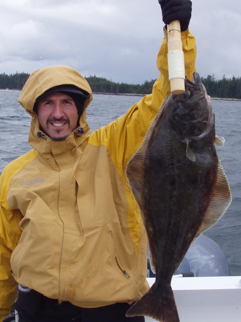 Angler in rain gear holding a halibut