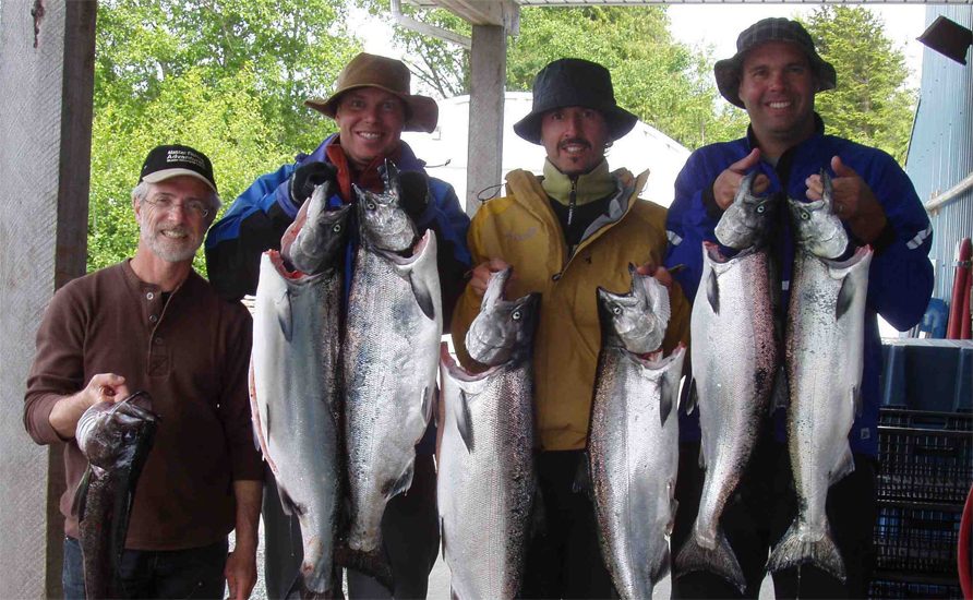 Group of anglers holding up freshly caught salmon