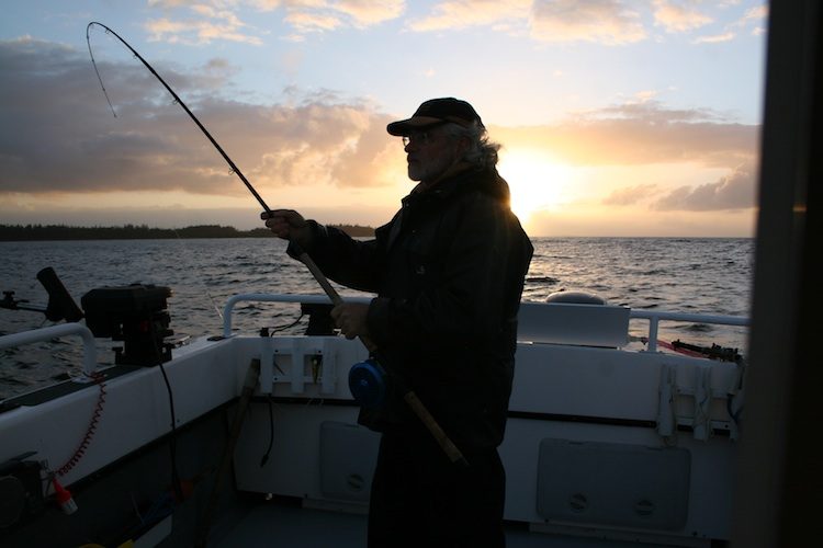 Angler silhouetted against the sunset, rod bent, off Masset